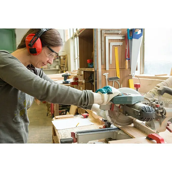 Magic Vision LED-Schutzbrille - Klar - Eine Frau benutzt eine Kreissäge mit Schutzbrille und Gehörschutz, um Holz zu schneiden. Das Werkzeug ist präzise und effektiv.