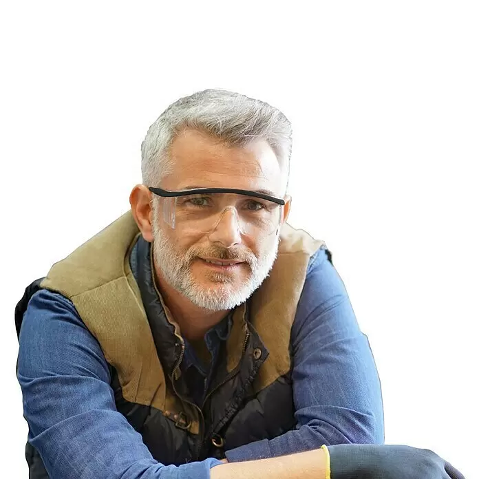 Magic Vision LED-Schutzbrille - Klar - Mann mit grauem Haar und Bart, trägt ein blaues Hemd, eine Steppweste und eine klare Schutzbrille, lächelt in die Kamera.