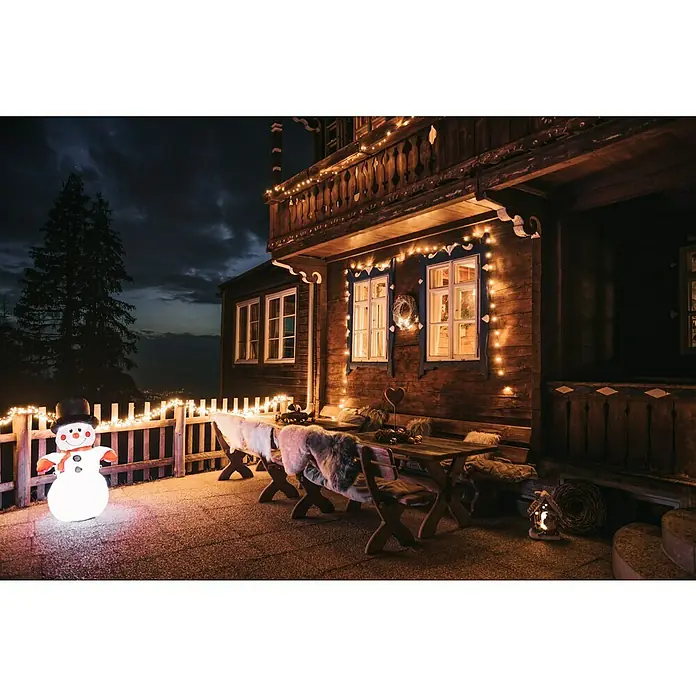 Guirnalda luminosa LED - Para exterior, 7,2 m, Color de luz: Blanco cálido, Número de bombillas: 96 ud., Funciona con pilas - Acogedor patio de invierno con decoración de muñeco de nieve. La figura del muñeco de nieve iluminada crea un ambiente festivo frente a la casa decorada.