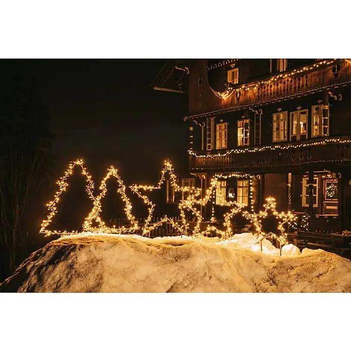 LED-Gartenstecker Stern M - Außen, Netzbetrieben, Höhe: 102 cm, Warmweiß - Weihnachtliche Sterne- und Baumbeleuchtung im Schnee vor einem festlich geschmückten Haus.