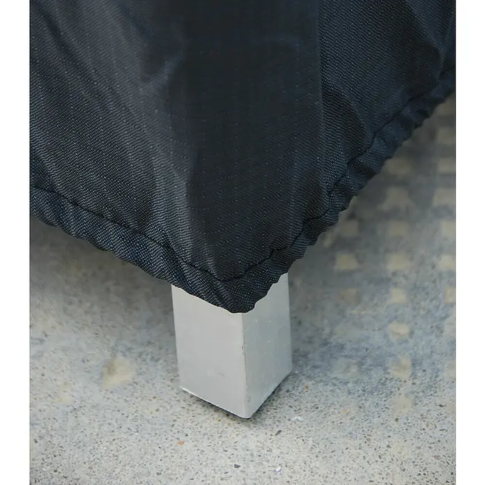 Funda protectora Boston - L x An x Al: 245 x 93 x 241 cm, Poliéster, 130 g/m², Negro - Primer plano de una funda protectora negra sobre un mueble, con una pata plateada que descansa sobre una superficie gris.