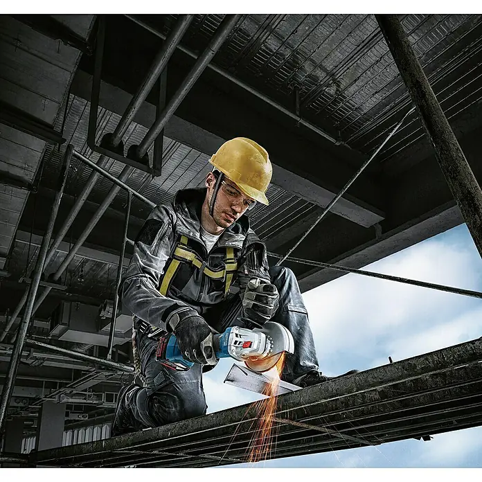 Bosch Professional AMPShare 18V Amoladora angular de batería GWS 18V-7 - 2 baterías, 4 Ah, Diámetro disco: 125 mm - Un trabajador de la construcción con casco usa una amoladora angular Bosch para cortar metal, saltando chispas.