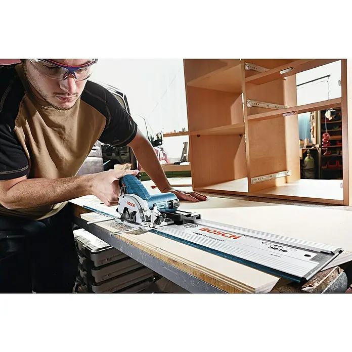 Bosch Professional Akku-Handkreissäge GKS 12V-26 - 12 V, 2 Akkus, 3 Ah, Leerlaufdrehzahl: 1.400 U/min - Ein Mann benutzt eine Bosch Kreissäge mit Führungsschiene, um präzise Holzzuschnitte für ein Möbelstück zu erstellen.