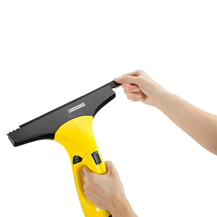Kärcher Limpiadora de cristales de batería WV2 Plus N - Sin batería, Volumen de recipiente: 0,1 l - Un limpiacristales amarillo Kärcher es sujetado por una mano, mientras que la otra mano está cambiando el labio de goma negro.