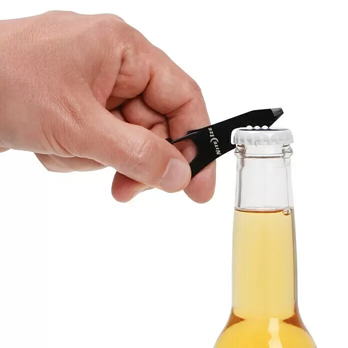 Nite Ize Multi-Tool DoohicKey ClipKey - Schwarz - Eine Hand benutzt einen schwarzen Multi-Tool Flaschenöffner, um den Kronkorken einer Bierflasche zu entfernen.