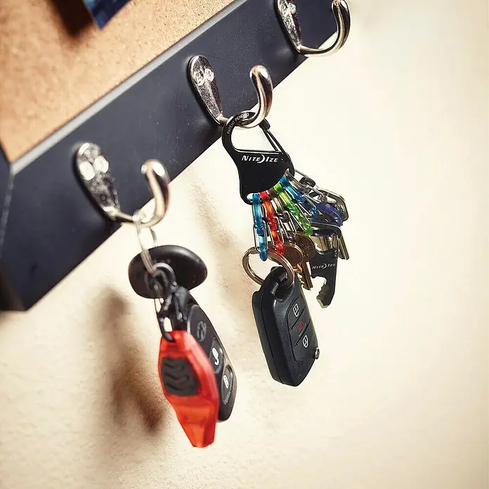 Nite Ize Mosquetón KeyRack - L x An: 12 x 2 mm, Acero inoxidable - Llavero con mosquetón Nite Ize y varias llaves colgadas en un riel de ganchos. Práctico para la organización.