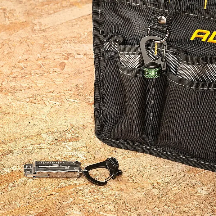 Nite Ize Doppelkarabiner Slidelock 360° Magnetic Lock - L x B: 19 x 2,05 cm, Aluminium, Anthrazit - Nahaufnahme eines Werkzeugorganisators mit Leatherman Micra und schwarzem Karabiner auf einer Holzoberfläche.