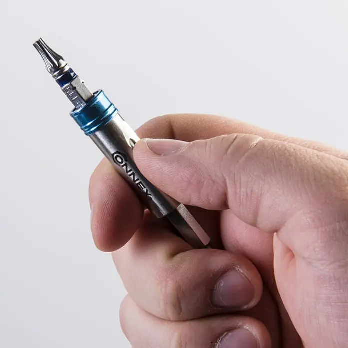 Connex Portabits para herramientas eléctricas COXB973100 - Acero - Primer plano de un hombre que sostiene un destornillador de precisión Connex con portabrocas y mango plateado.
