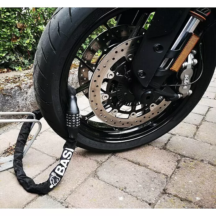 Basi Zahlen-Kettenschloss ZR 305 - Länge: 900 mm - Schwarzes BASI Kettenschloss mit Zahlencode sichert ein Motorradrad an einem Metallständer.