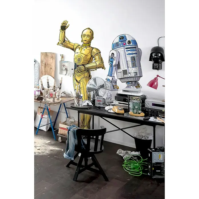 Komar Star Wars Dekosticker C-3PO XXL - B x H: 127 x 200 cm - Eine verspielte Szene mit C-3PO und R2-D2 Pappfiguren in einem kreativen, chaotischen Arbeitsbereich.