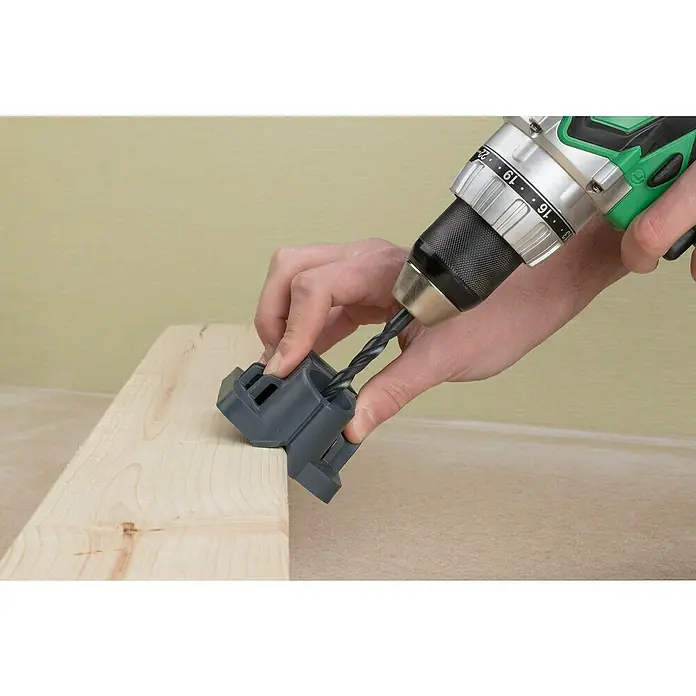 Wolfcraft Bohrhilfe - Lochdurchmesser: 35 mm - 12 mm - Ein grauer Bohrer wird mit einer Bohrmaschine durch eine Bohrschablone in ein Holzbrett gebohrt.