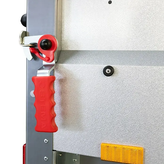 Stema Anhänger BASIC 750 Kippdeichsel - Nutzlast: 615 kg, Einachser, 201 x 108 x 33 cm, Ungebremst - Detailansicht eines Anhängerschlosses mit rotem Griff. Das Schloss ist an einer grauen Metalloberfläche montiert.