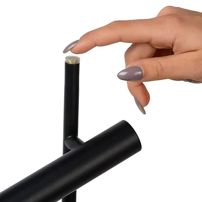 Lucide Stehleuchte Philon - Höhe: 140 cm, Schwarz, Anzahl Leuchtmittel: 2 Stk. - Detailaufnahme einer schwarzen Leuchte, bei der ein Finger den Schalter betätigt. Die Lampe ist modern und minimalistisch gestaltet.