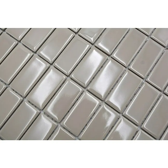 Mosaikfliese Stäbchen Uni ST 410 - 29,8 x 29,8 cm, Beige/Braun, Glänzend - Nahaufnahme von hellgrauen, glänzenden, rechteckigen Fliesen, die im Fischgrätenmuster verlegt sind und ein elegantes Mosaik bilden.