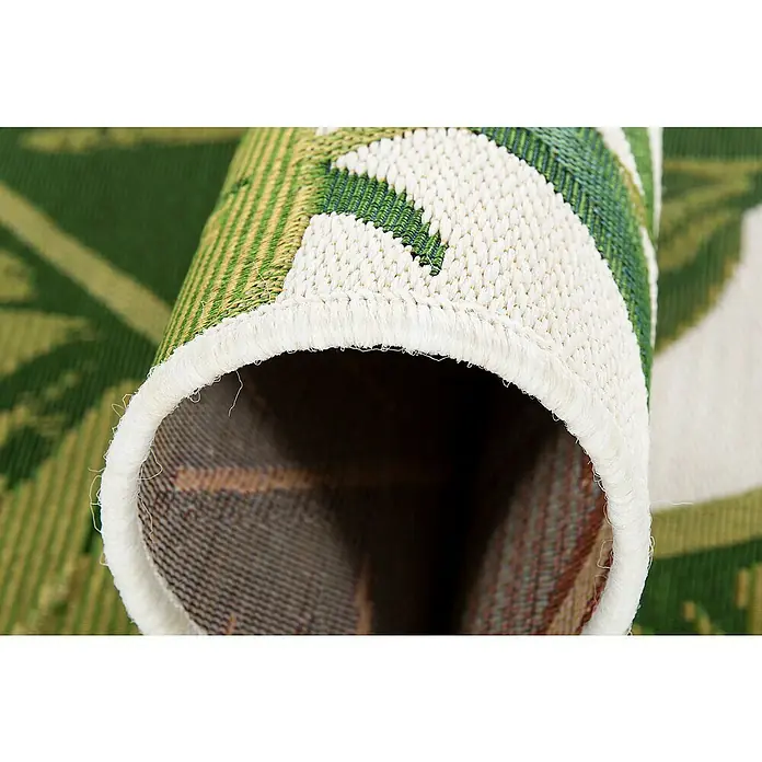 Outdoor-Teppich Kubana - Grün/Weiß, 230 x 160 cm, 75 % Polypropylen, 25 % Polyester - Detailansicht eines gerollten Teppichs mit grün-weißem Pflanzenmuster und gekettelten Kanten. Der Teppich zeigt eine robuste Textur und Verarbeitung.