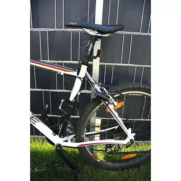 Basi Spiralschloss ZR 302 - Länge: 1.800 mm - Weißes Fahrrad mit roten und schwarzen Akzenten lehnt an einem dunklen Zaun.