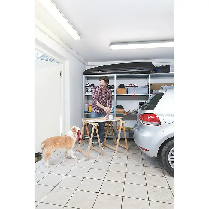 Osram LED-Feuchtraumlichtleiste Submarine - L x B x H: 65,5 x 7,2 x 8,6 cm, Lichtfarbe: Neutralweiß, 7 W, IP65 - Ein Mann lackiert Holz auf einer Werkbank in seiner Garage, während sein Hund mit einer Leine daneben steht.