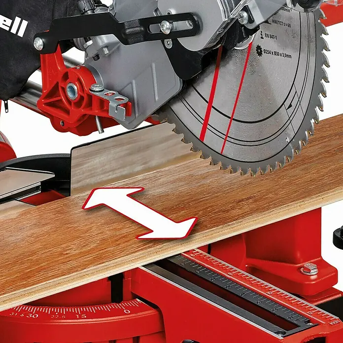 Einhell Sierra ingletadora telescópica TC-SM 2531/2 U - 1.900 W, Diámetro hoja de sierra: 254 mm, Número de revoluciones de marcha en vacío: 1.900 r.p.m. - Primer plano de una sierra de inglete Einhell con una tabla de madera y una flecha blanca que indica la dirección del corte.