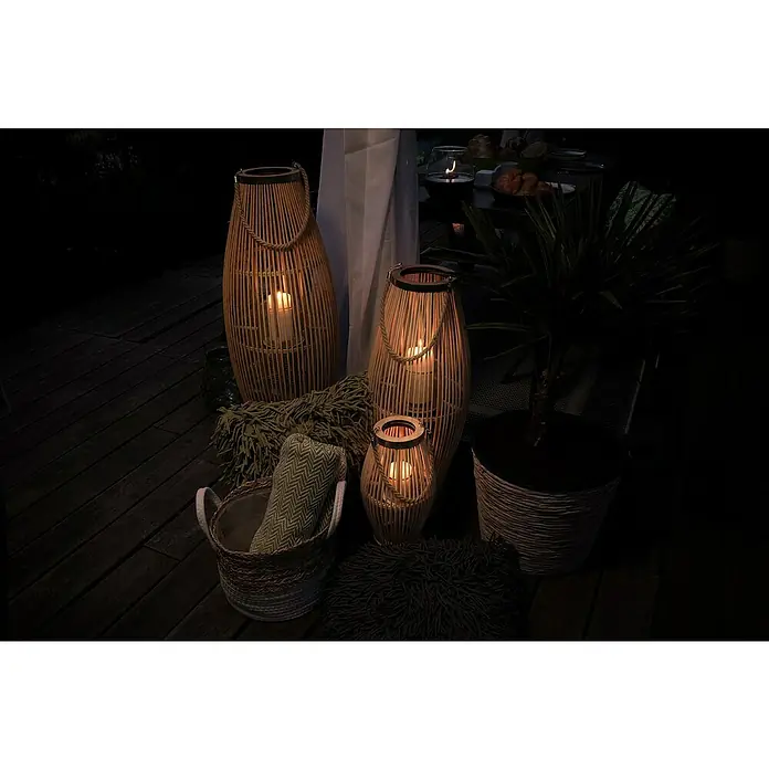 Farolillo alto Tarik - L x An x Al: 28 x 28 x 72 cm, Natural - Escena decorativa con faroles de bambú de varios tamaños, una planta y textiles acogedores en una terraza de madera oscura.
