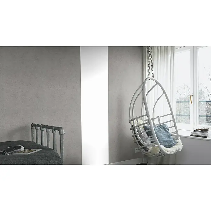 Rasch Kimono Vliestapete - Grau, Uni, 10,05 x 0,53 m - Ein stilvolles Interieur mit einem grauen Bettgestell und einem hängenden Korbsessel mit Kissen in der Nähe eines Fensters.