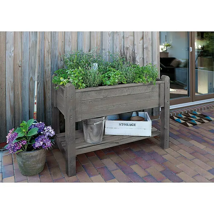 Promadino Kräuterhochbeet - 114 x 60 x 84,5 cm, Grau - Hochbeet aus Holz im Garten. Auf dem Beet wachsen Kräuter, darunter befindet sich eine Ablage für Gartengeräte.