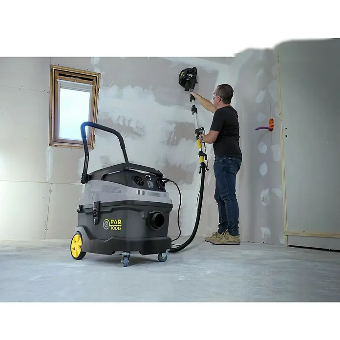Fartools Aspirador en seco y húmedo eléctrico MF35 - 1.600 W, Volumen de recipiente: 35 l, Con bolsa - Aspiradora FAR Tools en uso al lijar una pared. El dispositivo destaca por su alta potencia de aspiración y su facilidad de uso.