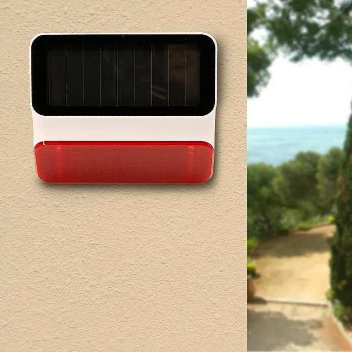 Avidsen Funk-Solaraußensirene - Passend für: Avidsen Alarm-Kit Modell 100720 & 100731, 100 dB, Außen - Das Bild zeigt eine solarbetriebene Alarmsirene mit einer roten Warnleuchte, die an einer hellen Wand befestigt ist, ideal für Sicherheitsanwendungen.