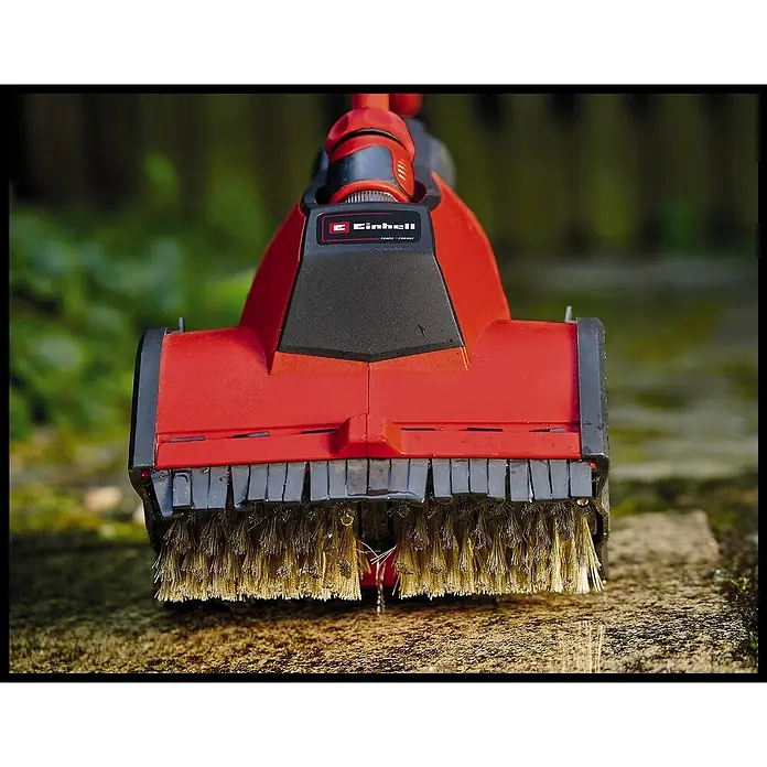 Einhell Power X-Change 18V Fugenbürste Zubehör ULTRA (Stein) - Arbeitsbreite: 195 mm, Metall - Nahaufnahme einer roten Einhell Fugenbürste mit rotierenden Metallborsten zum Reinigen von Pflastersteinen im Außenbereich.