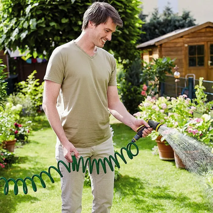 Neptun Hauswasserwerk NHW-E 68 - 680 W, Max. Fördermenge: 3.800 l/h, Max. Druck: 3,6 bar - Ein Mann bewässert seinen Garten mit einem spiralförmigen Gartenschlauch, der sich leicht handhaben lässt und die Gartenarbeit erleichtert.