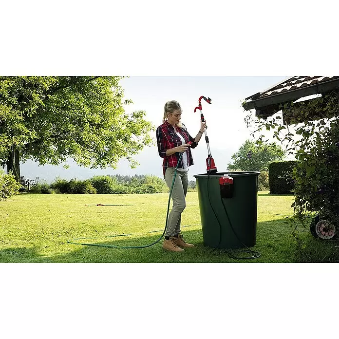 Einhell Power X-Change 18V Akku-Klarwasserpumpe GE-PP 18 RB LI SOLO - 18 V, Ohne Akku, Max. Fördermenge: 3.000 l/h - Eine Frau schließt einen grünen Schlauch an eine rot-schwarze Tauchpumpe in einer Regentonne zum Bewässern an.