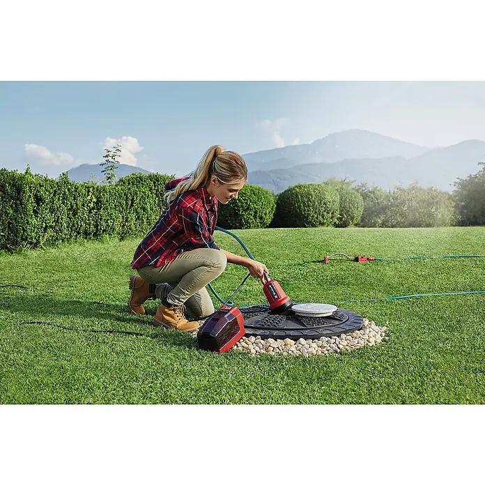 Einhell Power X-Change 18V Akku-Klarwasserpumpe GE-PP 18 RB LI SOLO - 18 V, Ohne Akku, Max. Fördermenge: 3.000 l/h - Frau mit Einhell-Gartenpumpe an einem Brunnen.