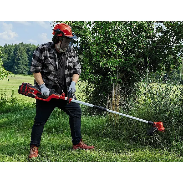 Einhell PXC 18V Multiherramienta de jardín 36VGE-LM 36/4in1 + Batería y cargador PXC-Starter kit - 36 V, Iones de litio, 4 Ah, 2 baterías - Hombre usando un recortador de césped inalámbrico Einhell en el jardín. El recortador es rojo y negro.