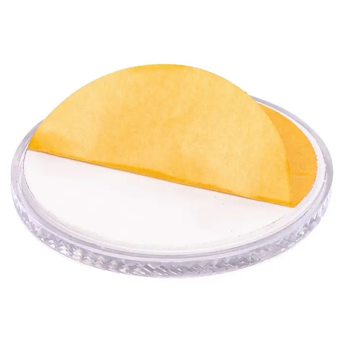Stema Reflektor - Weiß, Länge: 60 mm - Ein rundes, transparentes Pad mit einer gelben Schutzfolie, ideal für Möbel oder andere Oberflächen, um Kratzer zu vermeiden.
