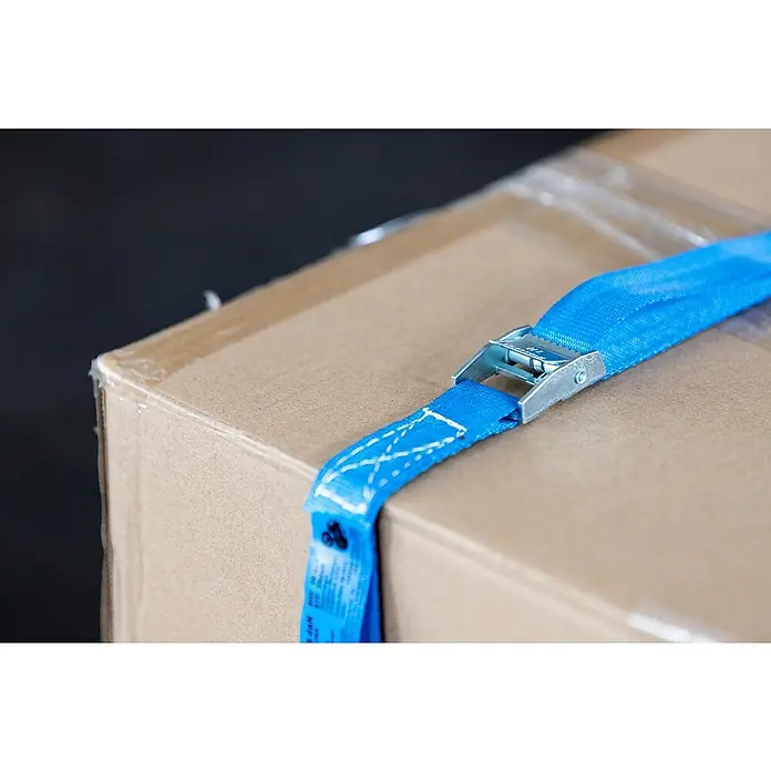 Stema Spanngurt mit Klemme - 2,5 m x 2,5 cm, Belastbarkeit: 125 kg - Nahaufnahme eines Kartons mit einem blauen Zurrgurt, der das Paket sichert. Der Gurt ist mit einem Metallschnellverschluss versehen.