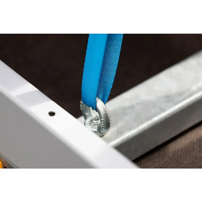 Stema Spanngurt mit Klemme - 2,5 m x 2,5 cm, Belastbarkeit: 125 kg - Nahaufnahme eines blauen Gurtes, der an einem metallischen Befestigungspunkt an einem Anhänger befestigt ist.