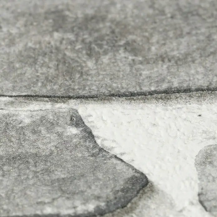 Rasch Papiertapete - Grau, Steinoptik, 10,05 x 0,53 m - Nahaufnahme einer grauen Steinmauer-Tapete, die eine realistische Textur und ein dreidimensionales Aussehen aufweist.