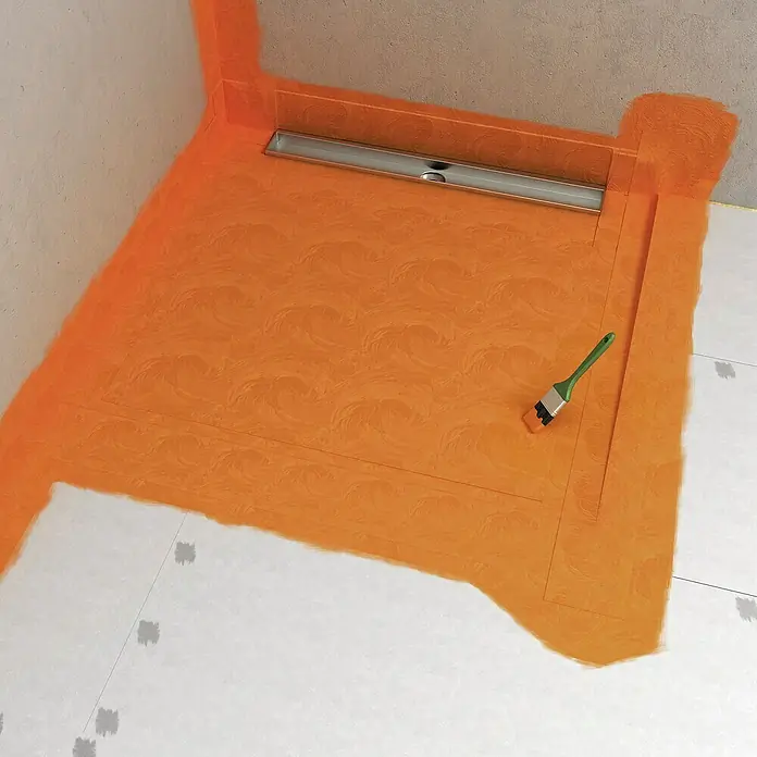 Fermacell Flüssigfolie - 5 kg - Detailaufnahme einer Badezimmerabdichtung mit einer Duschrinne. Die Abdichtung ist orange und eine Bürste liegt daneben.