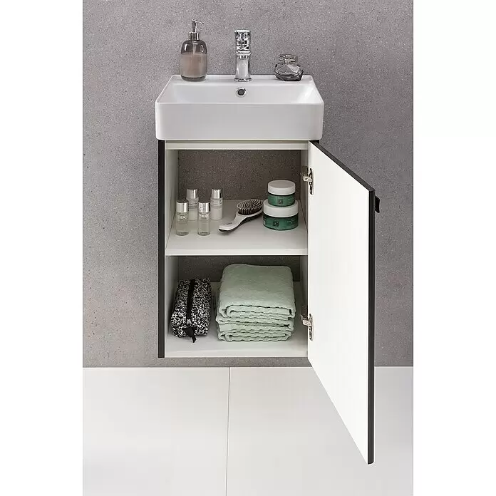 Camargue Visita Mueble bajo de lavabo Visita - 40 x 40 x 60 cm, Antracita - Mueble de baño blanco montado en la pared con lavabo y puerta de armario abierta revelando artículos de tocador y toallas verdes.