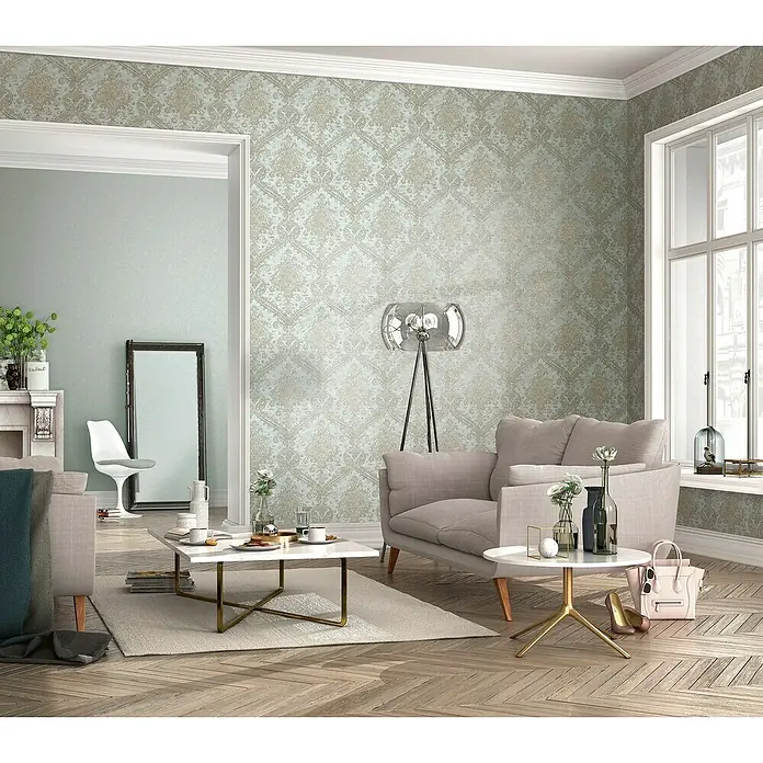 Rasch Vliestapete - Gold/Blau, Ornament, 10,05 x 0,53 m - Ein helles Wohnzimmer mit gemusterter Tapete, modernem Sofa und stilvollen Möbeln. Die Einrichtung strahlt Eleganz und Komfort aus.