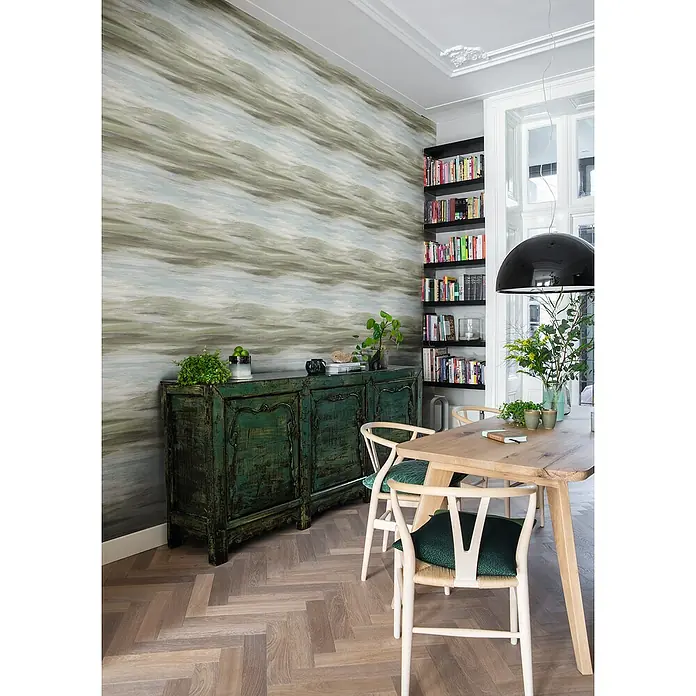 Rasch Vliestapete - Grün/Braun/Blau, Grafisch, 10,05 x 0,53 m - Aufnahme eines Esszimmers mit einem rustikalen grünen Schrank und einem Holztisch mit weißen Stühlen auf einem Fischgrätparkett.