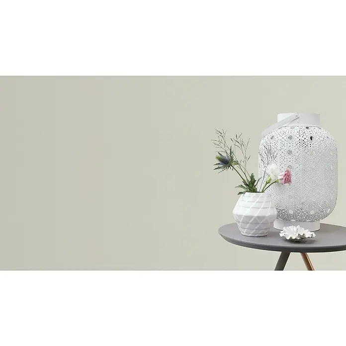 Rasch Vliestapete - Weiß/Creme, Uni, 10,05 x 0,53 m, Matt, Feine Struktur - Das Bild zeigt eine dekorative weiße Laterne, eine weiße Vase mit Blumen und eine kleine weiße Dekoschale auf einem grauen Tisch.