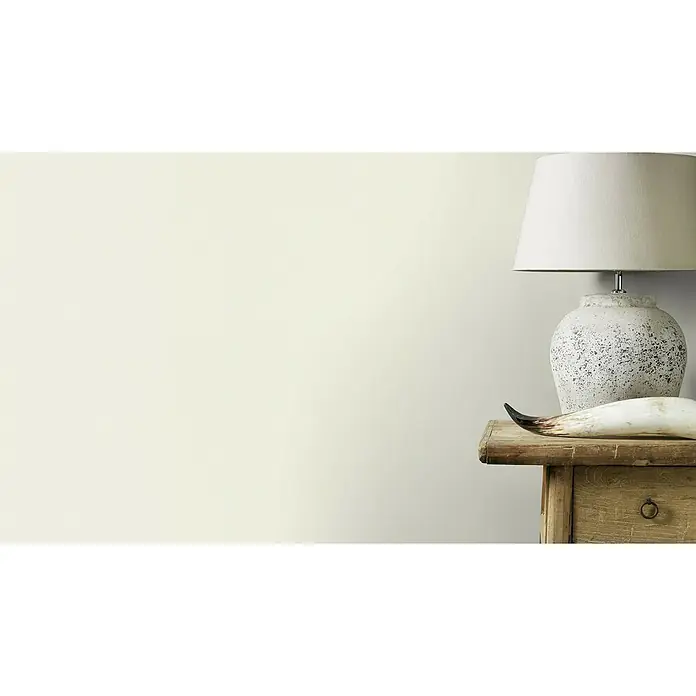 Rasch Vliestapete - Weiß/Creme, Uni, 10,05 x 0,53 m, Matt, Feine Struktur - Elegante Tischleuchte mit cremefarbenem Schirm und rustikalem Steinfuß, platziert auf einem Vintage-Holztisch mit dekorativem Horn.