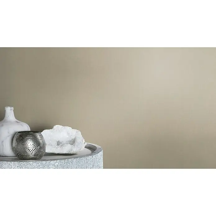 Rasch Vliestapete - Braun, Uni, 10,05 x 0,53 m, Matt, Feine Struktur - Nahaufnahme von Wohnaccessoires: einer Marmorvase, einem silbernen Kerzenhalter und einem weißen Quarz auf einem verzierten Tisch.