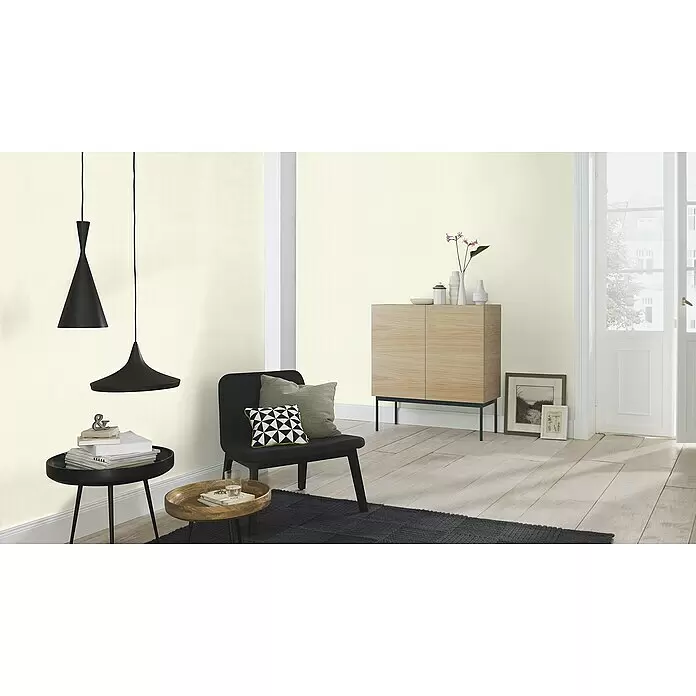 Rasch Unsere Besten 2022 Vliestapete - Creme, Uni, 10,05 x 0,53 m - Zwei schwarze Pendelleuchten hängen über einem Beistelltisch und Stuhl in einem modernen Wohnraum.
