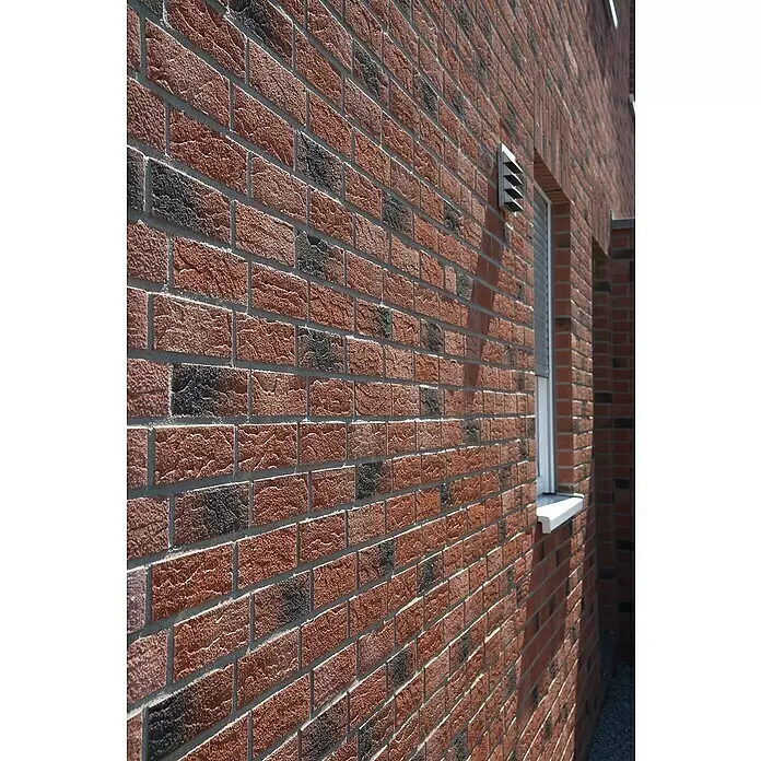 Celina Klinker Verblendstein Handform Old Millhouse - 5,2 x 24 cm, Rot/Grau, Steinoptik - Texturierte rot-dunkle Ziegelwand eines Gebäudes mit Fenster, Rollladen und Lüftungsgitter.