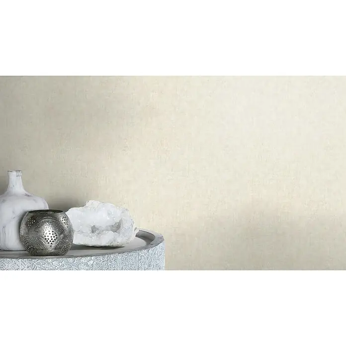 Rasch Factory 4 Vliestapete - Creme, Uni, 10,05 x 0,53 m - Nahaufnahme einer Tischdekoration mit einer Vase, einem Metallwindlicht und einem weißen Kristall, die eine elegante und moderne Atmosphäre schaffen.