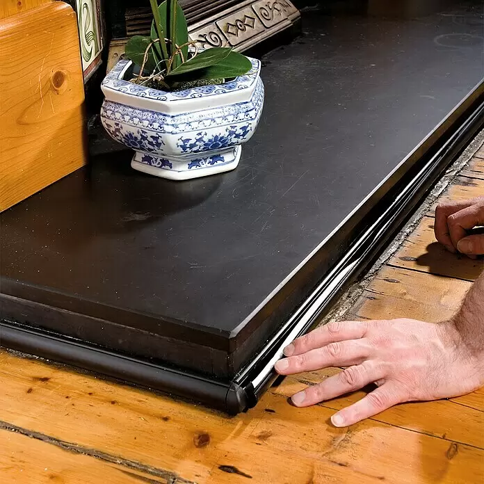 D-Line Kabelkanal Halbrund - 1 m, 30 x 15 mm, Schwarz - Schwarzer Kaminschutz wird auf Holzboden montiert, um Sicherheit zu gewährleisten und die Umgebung zu schützen.