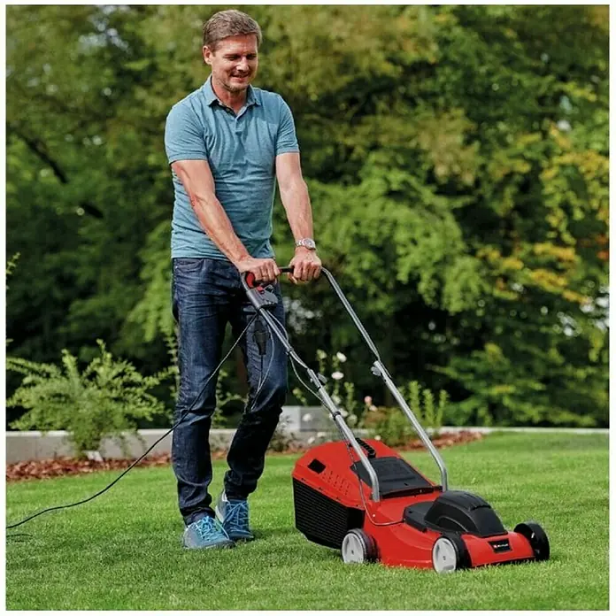 Einhell Cortacésped eléctrico GC-EM 1032 - 1.000 W, Ancho de corte: 32 cm - Un hombre corta el césped con un cortacésped eléctrico rojo Einhell en el jardín. El cortacésped es el elemento central.