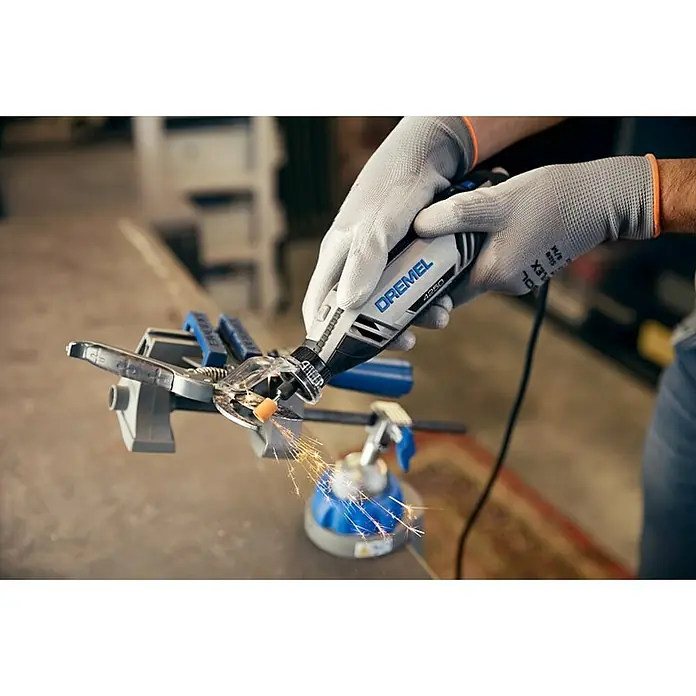 Dremel Multifunktionswerkzeug 4250-3/45 - 175 W, 5.000 U/min - 35.000 U/min - Nahaufnahme eines Dremel 4250 Multifunktionswerkzeugs in Aktion, das mit einem Schutzaufsatz und Handschuhen bedient wird, während es Funken sprüht.