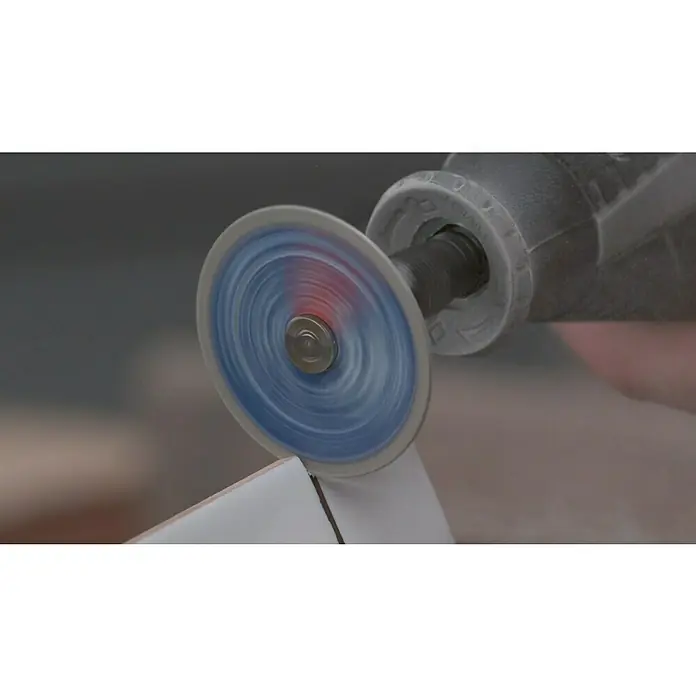 Dremel EZ SpeedClic Diamant-Trennscheibe Max Life SC545DM - Durchmesser: 38,1 mm, Passend für: Dremel Multifunktionswerkzeug - Nahaufnahme eines rotierenden Trennschleifers beim Schneiden eines weißen Fliesenstücks. Das Werkzeug ist ein Dremel oder ähnliches.